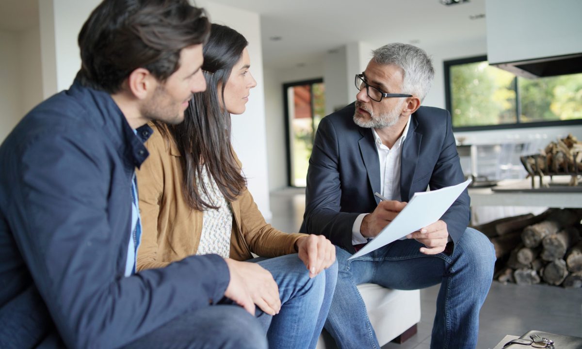 Couple with real-estate agent looking at contract in modern house